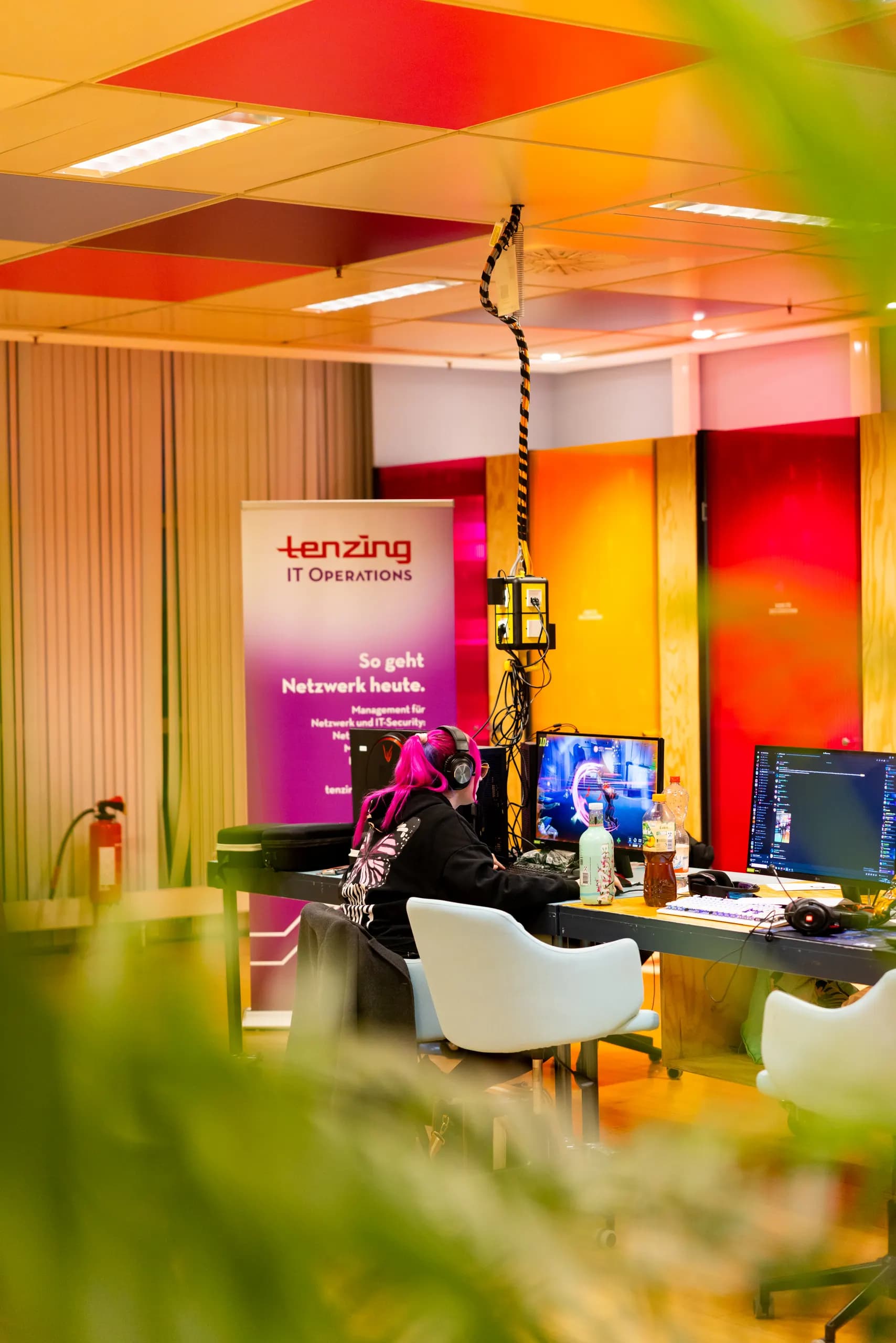 Spielerin mit pinkem Headset an ihrem Platz in der LAN-Halle